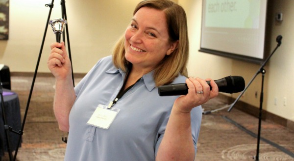 Jenny Doty with the Community Food Systems Team holding a microphone and bell